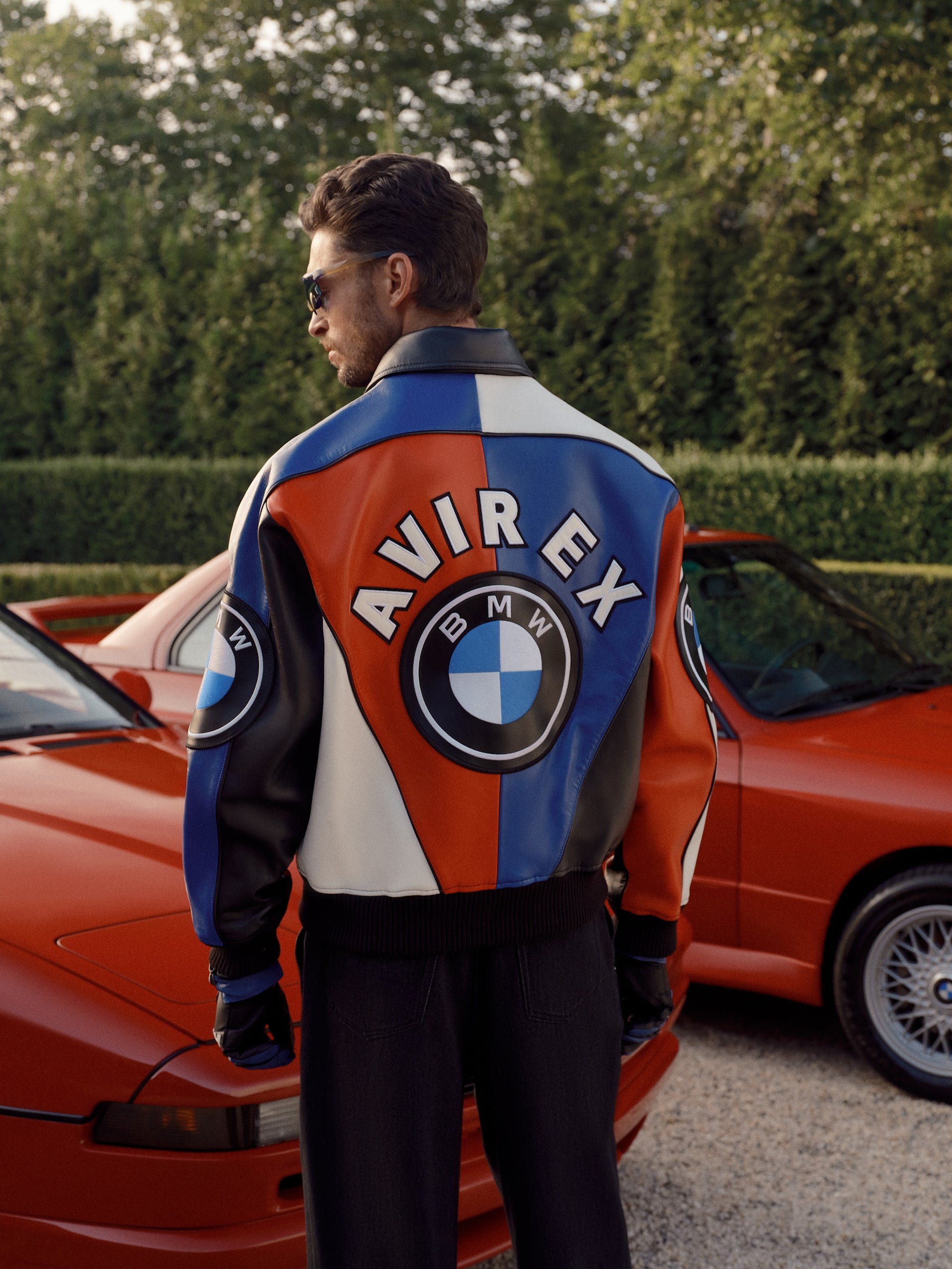 Kith and AVIREX for BMW colour-blocked leather jacket photographed beside orange BMW coupes